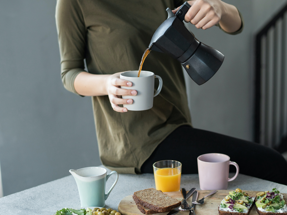 Woman In Green Top Pouring Coffee In A White Mug 37542962