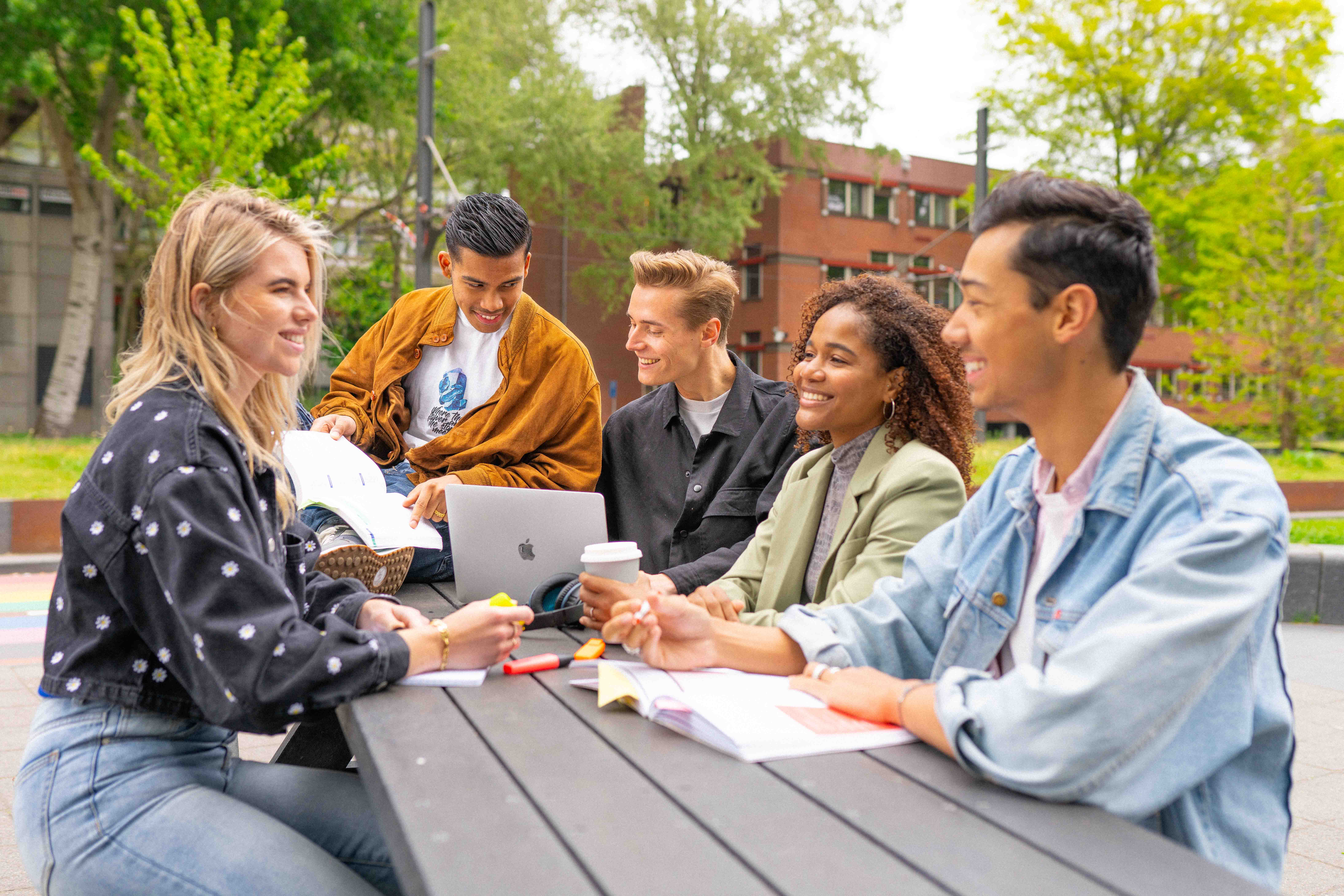 Studenten buiten aan picknick tafel