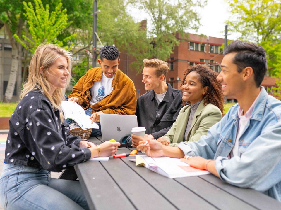 Studenten buiten aan picknick tafel
